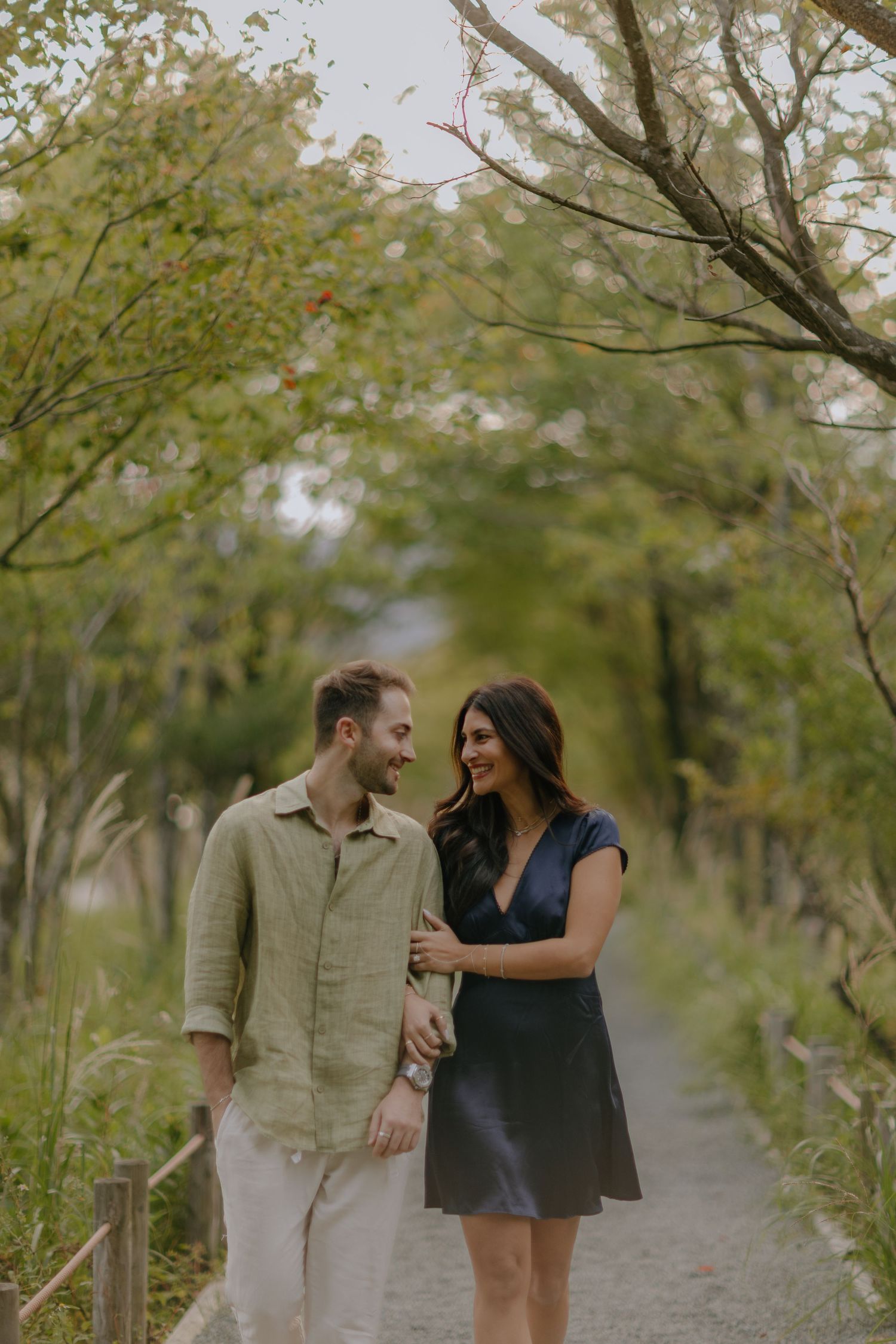 A couple shares a romantic moment while walking together on a tree-lined path during a warm autumn day at Hakone Japan