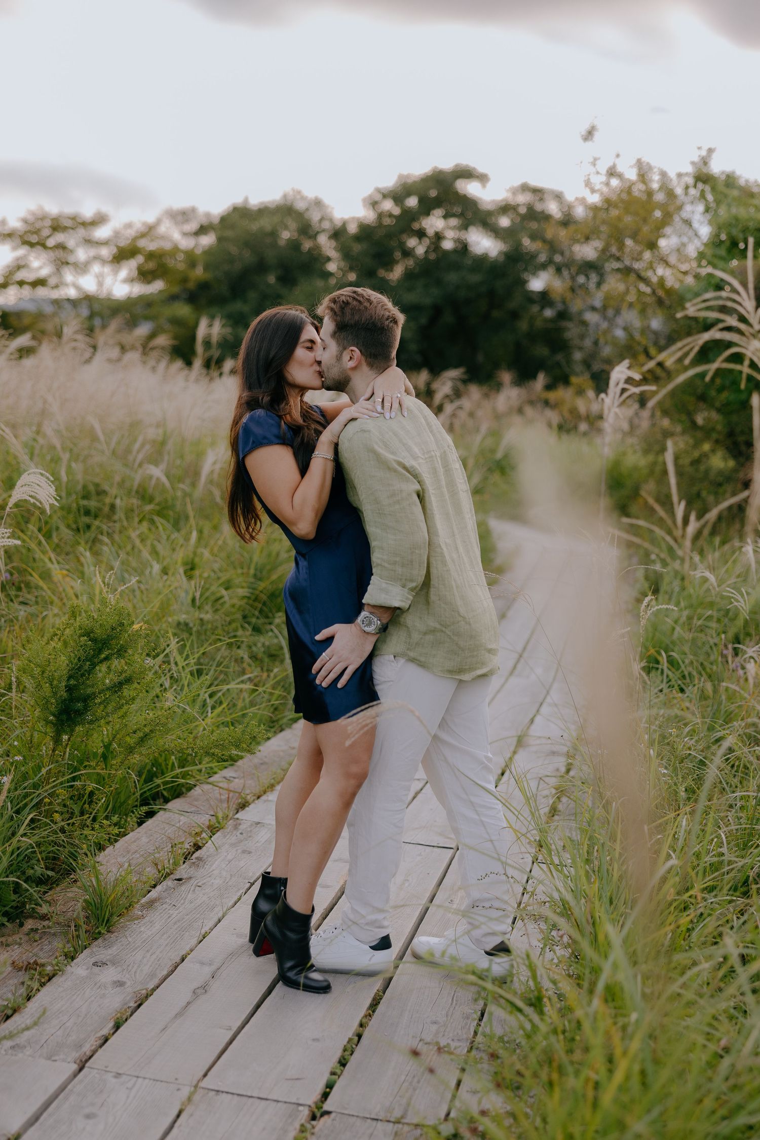 A couple shares romantic moments on a wooden boardwalk surrounded by tall grass during a photo session at Hakone Japan