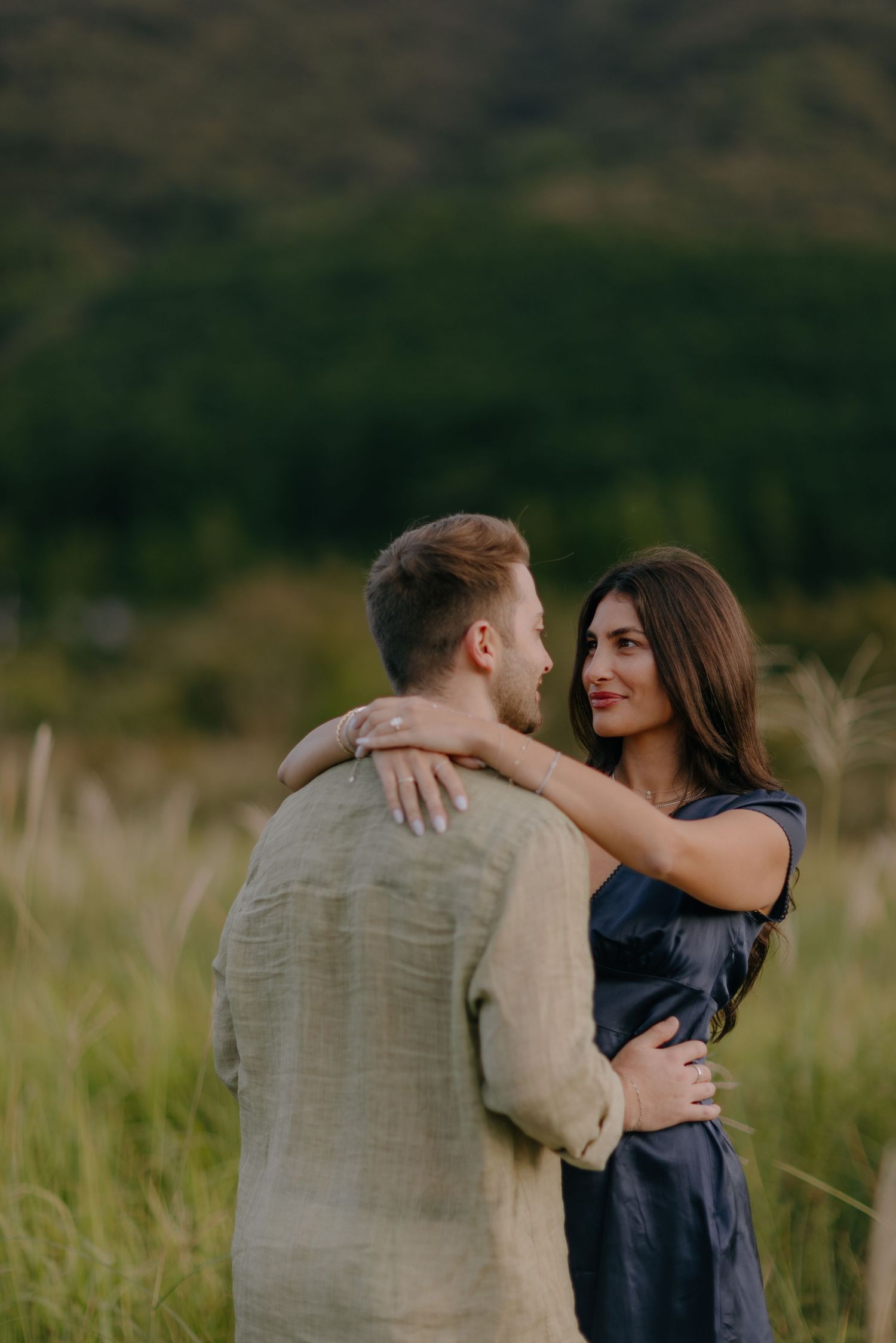 Romantic couple embraces in tall grass field during golden hour with mountains in background at Hakone Japan
