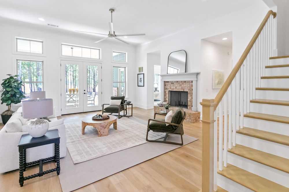 Modern white staircase with wooden treads and glass railings leads up to a bright, open living space.