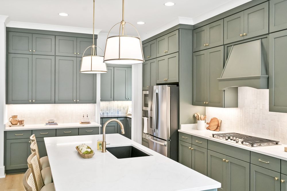 Modern gray kitchen with shaker cabinets, white countertops, and brass hardware details.