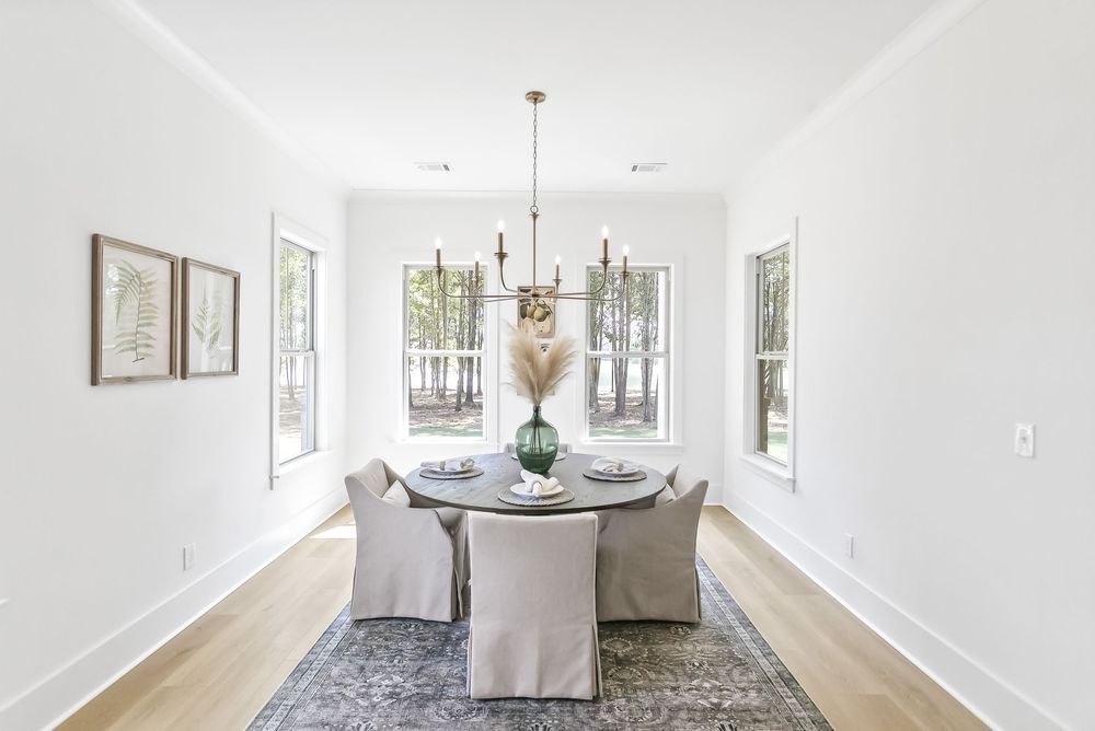 A bright white hallway with hardwood floors features framed artwork and leads to a sunlit living area.