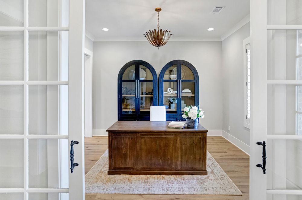 Elegant white hallway with arched doorways and hardwood flooring features modern pendant lighting and neutral decor.