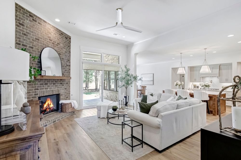 Modern living room with white walls, hardwood floors, and a cozy brick fireplace creates an inviting atmosphere.