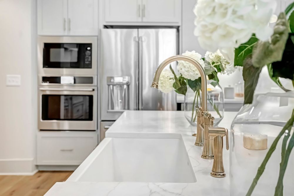 Luxury kitchen with stainless appliances, gold faucet, white marble counters and fresh hydrangea flowers.