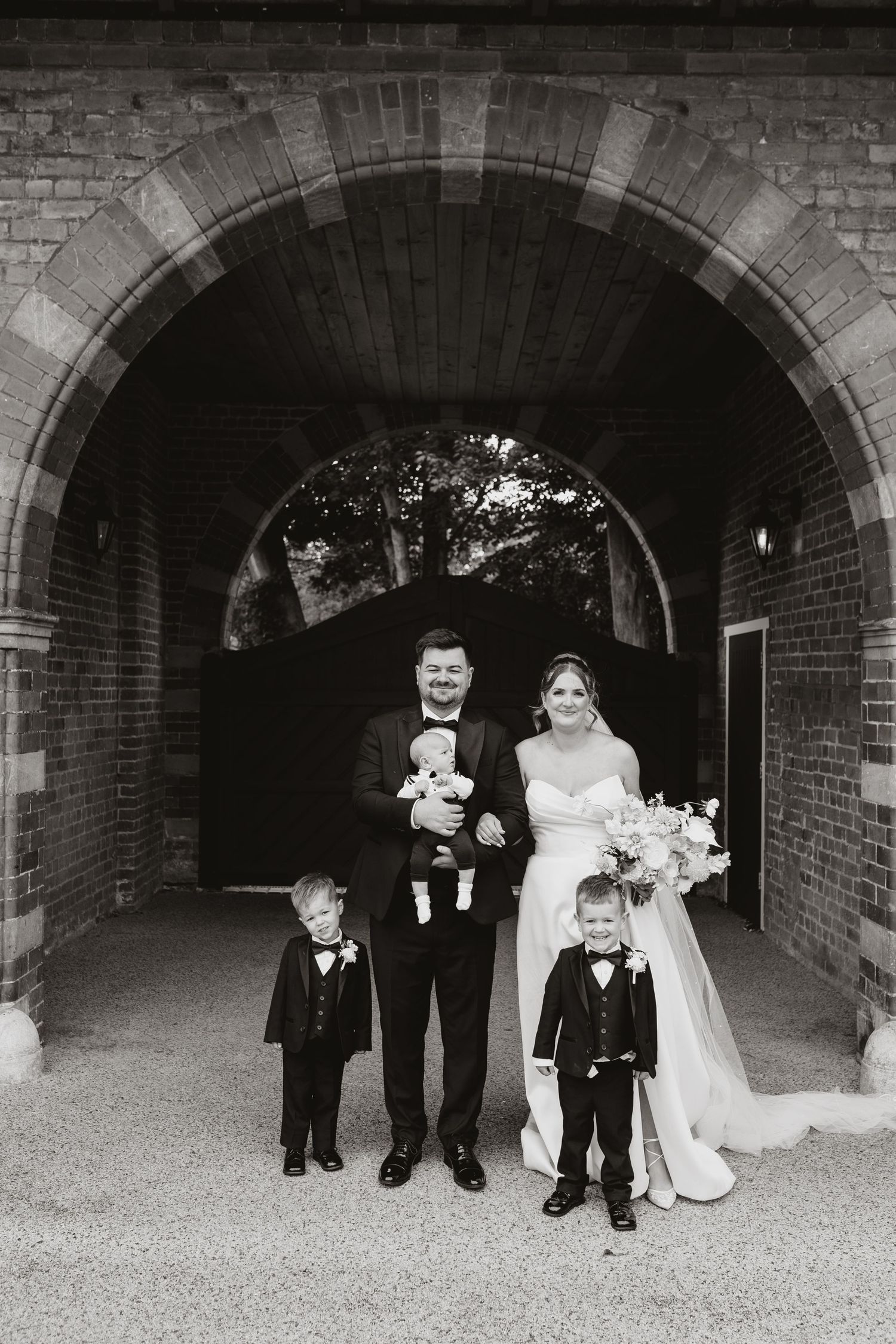 A wedding party stands under brick archways in a series of black and white photographs showing progression of movement at Chester Zoo,