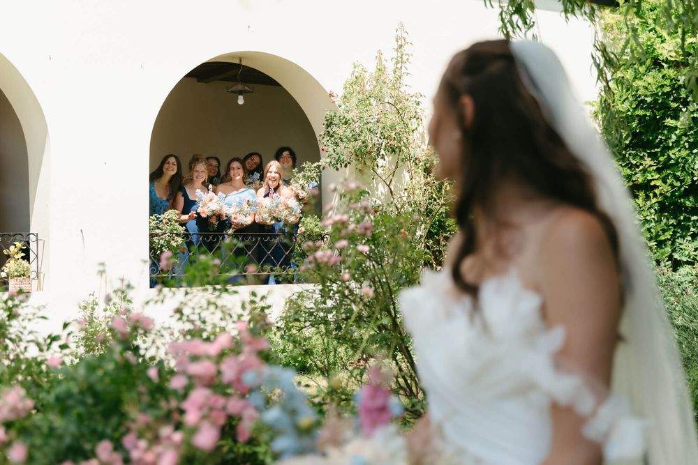 A romantic outdoor wedding scene with white arches and pink roses in a lush garden setting.