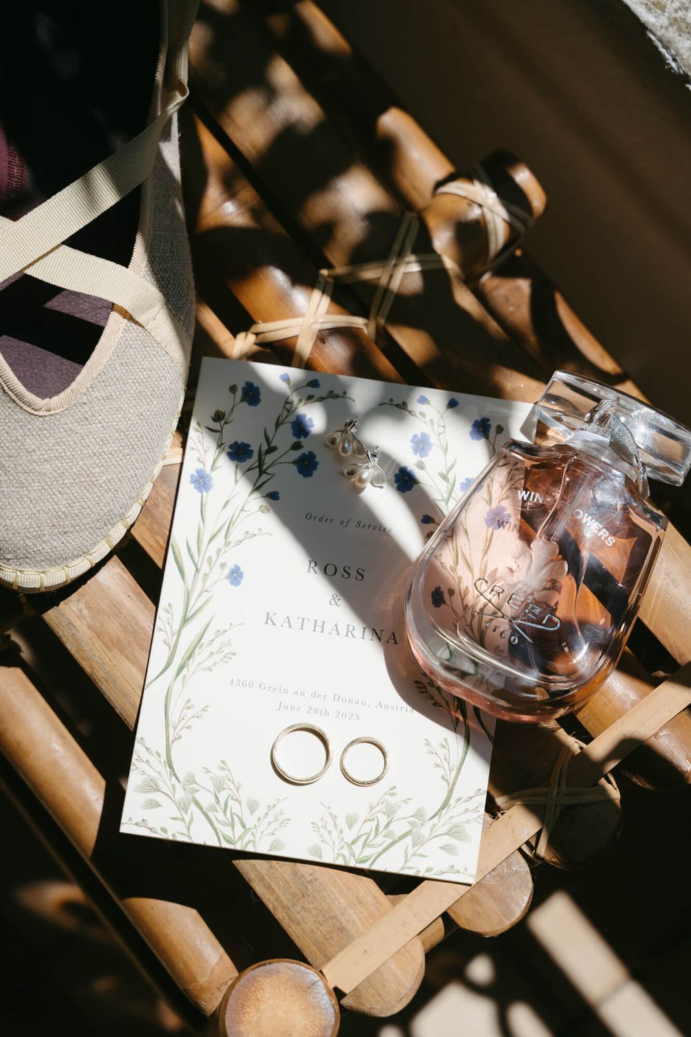 Wedding rings and invitation details captured in dramatic window light creating artistic shadows.