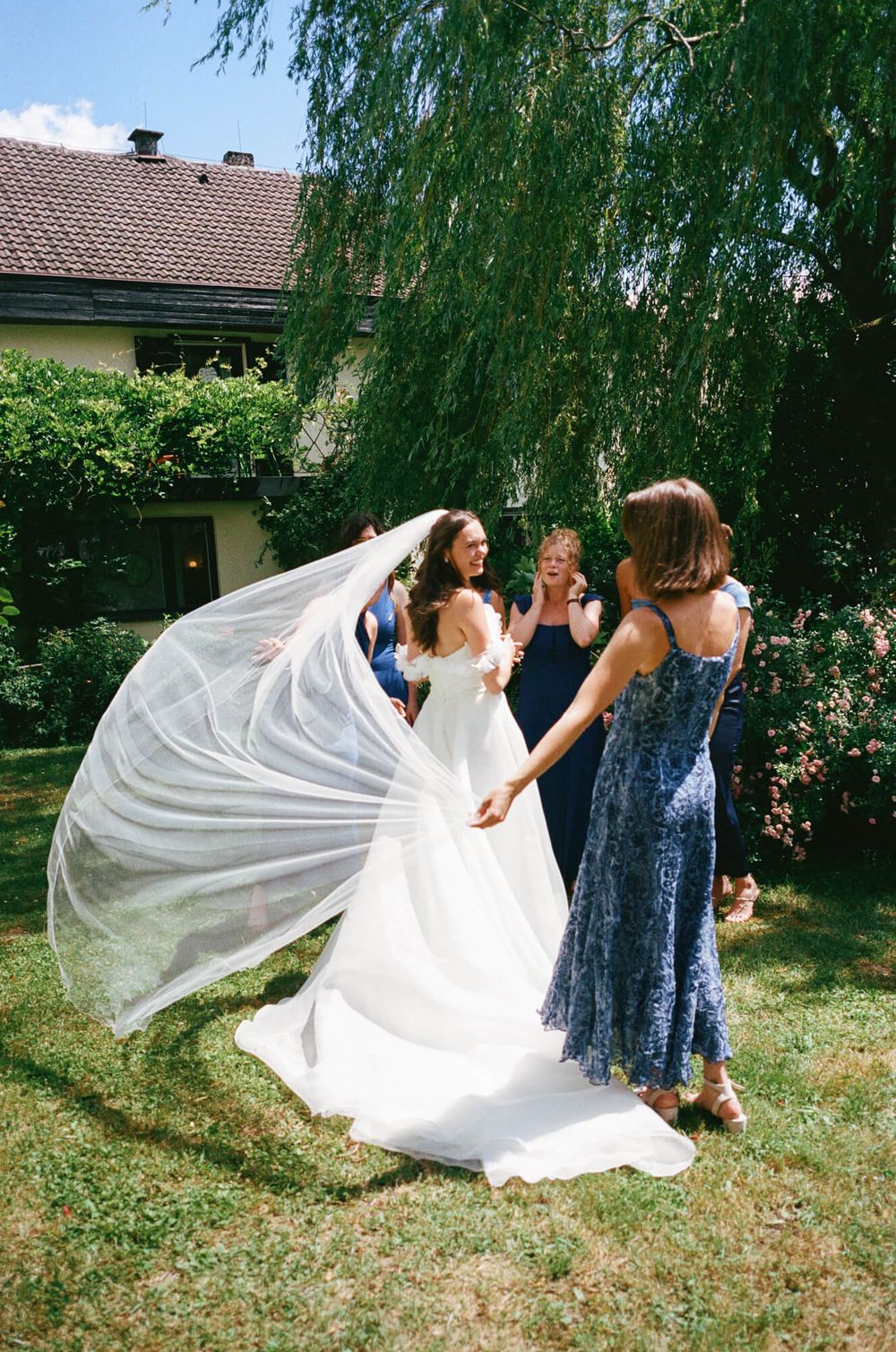 A sequence showing a bride twirling her white dress in an outdoor garden with bridesmaids in blue dresses nearby.