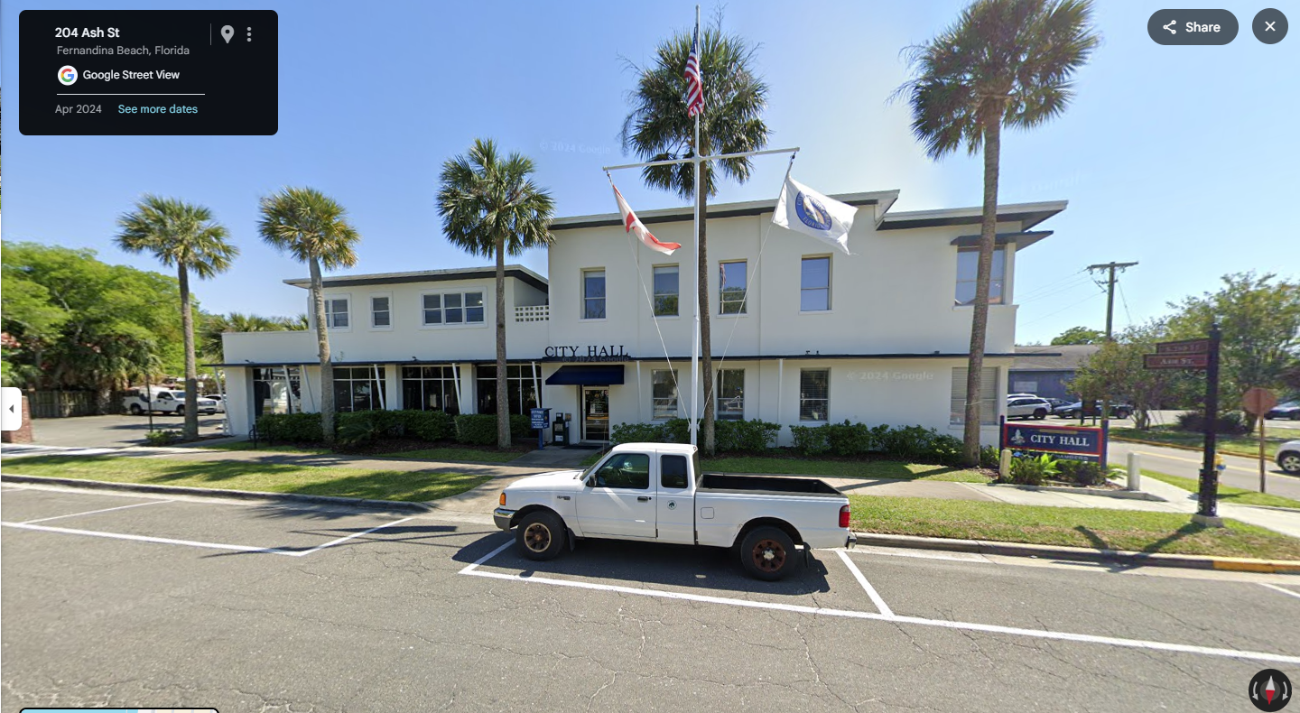 Google Street View of a white government building with palm trees in Florida coastal town.