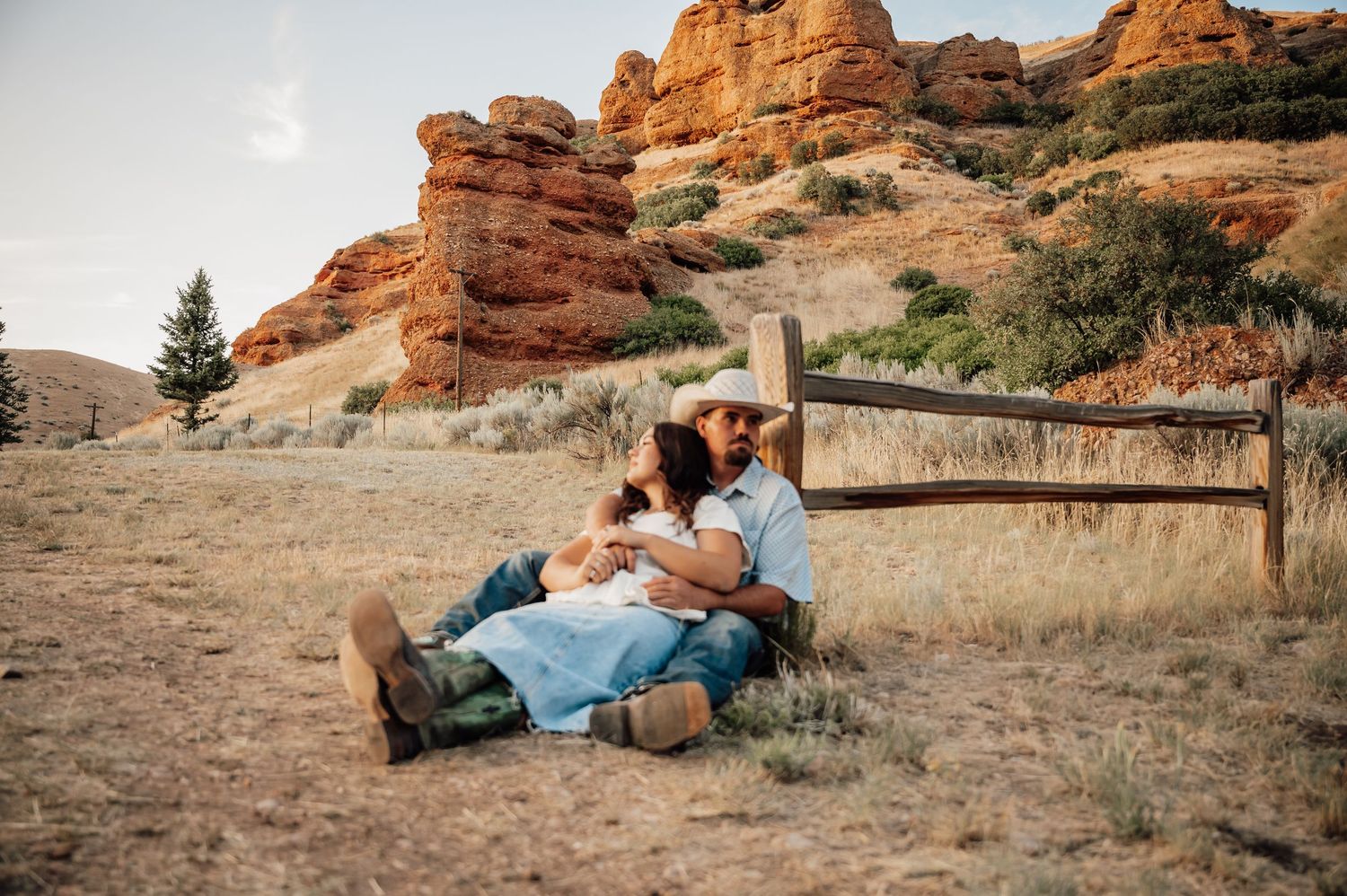 A couple shares intimate moments against a backdrop of red rock formations at sunset.