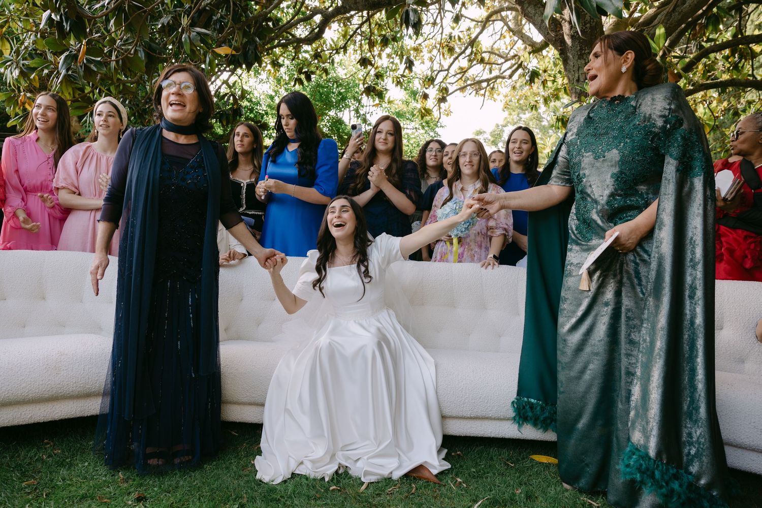 Wedding party poses together outdoors wearing coordinated dark and light formal attire.