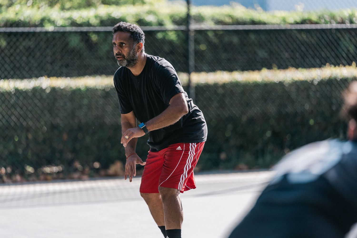 Basketball players dribbling and practicing moves on an outdoor court during a sunny day.