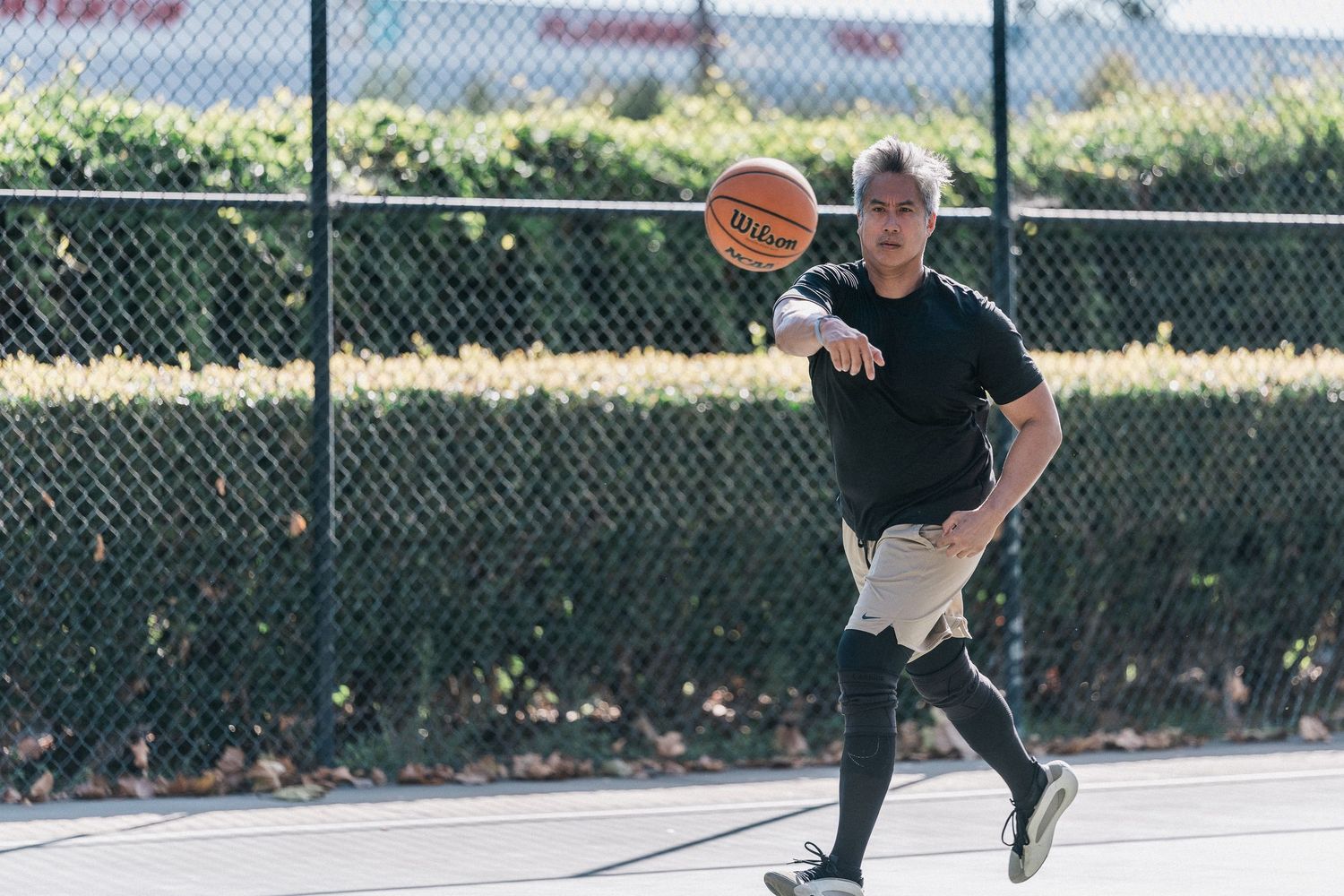 Basketball player dribbles on outdoor court while practicing moves in athletic attire.