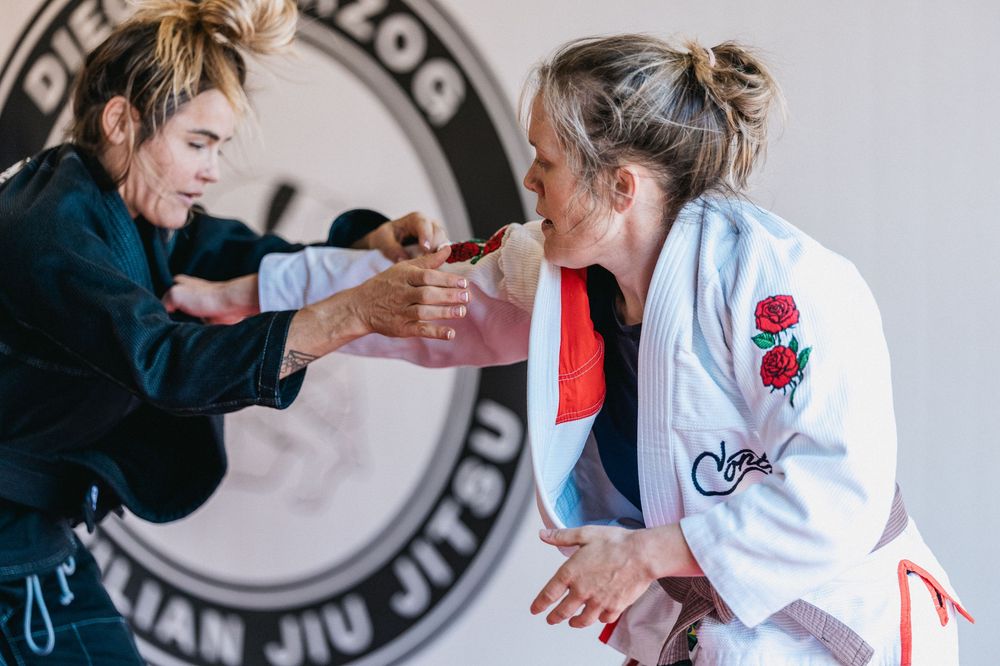 Students practicing martial arts techniques in white uniforms with red details during a training session.