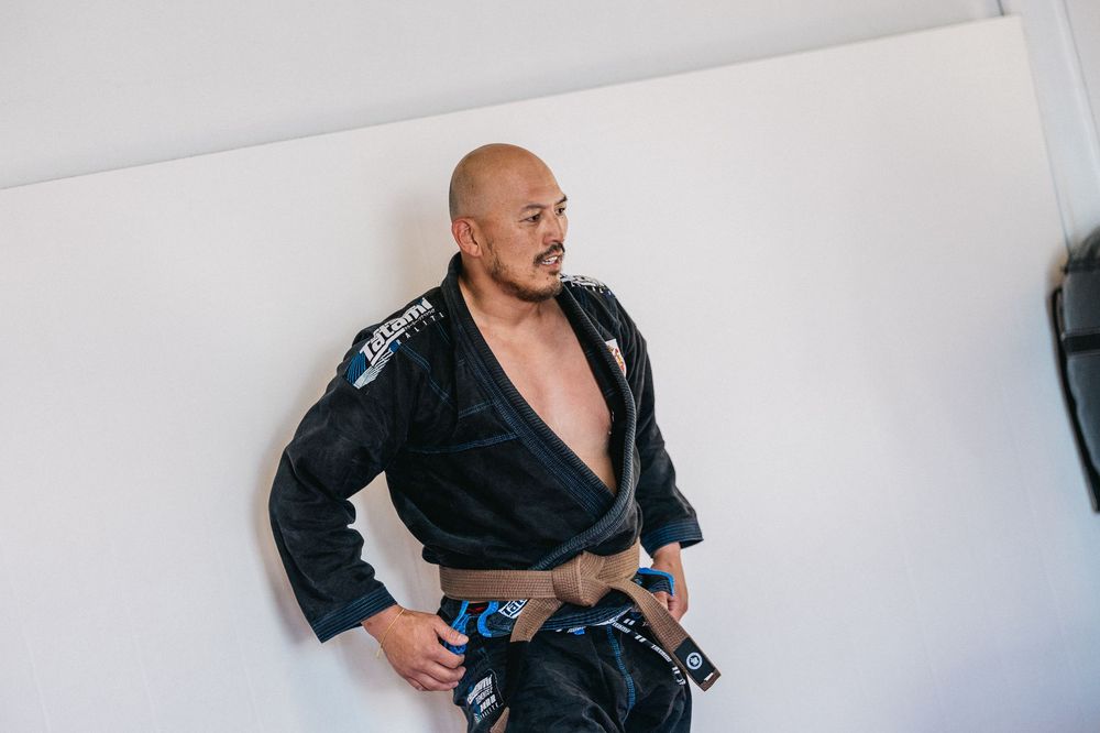 Person wearing a black martial arts gi demonstrates traditional jiu-jitsu techniques in a sequence of movements.