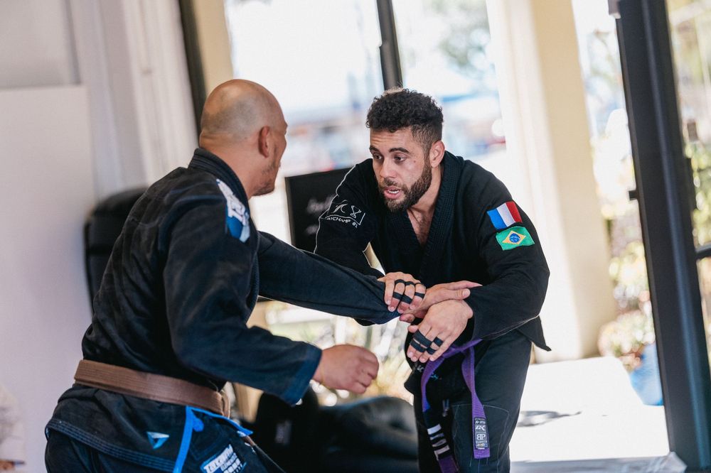 Two people practicing Brazilian Jiu-Jitsu techniques on a mat during a training session.