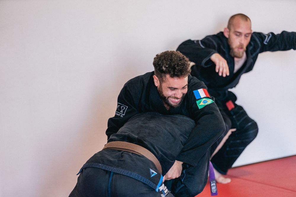 Two people practicing martial arts techniques on red mats during a training session.