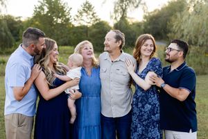 Family members share candid moments of laughter and hugs while posing in coordinated outfits outdoors. Sussex County NJ Photographer
