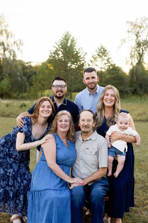 Extended family gathering outdoors with multiple generations wearing coordinated blue and navy outfits. Sussex County NJ Photographer