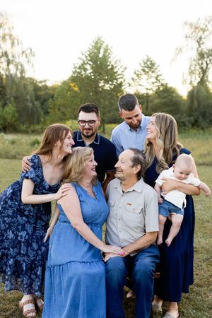 A multi-generational family embraces and shares genuine laughter during a casual outdoor photoshoot.