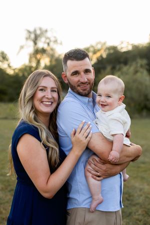 A family shares joyful moments together outdoors during a summer photo session.