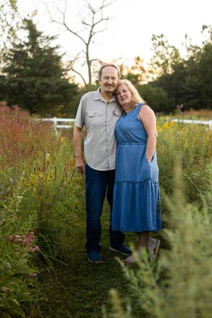 A couple embraces in a wildflower field during sunset wearing coordinating casual outfits.