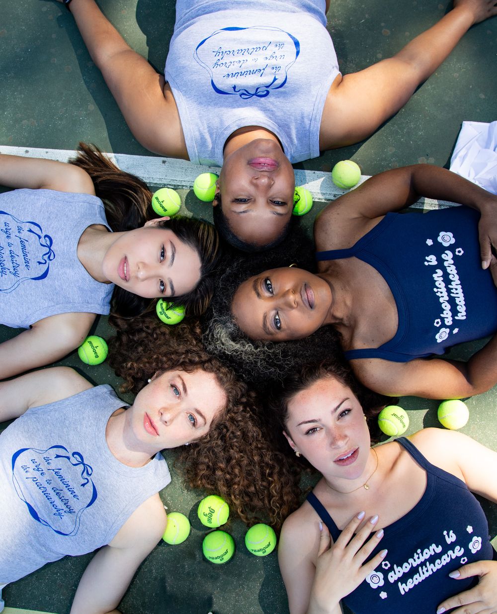 Group lying on floor with tennis balls arranged around them in matching workout attire.