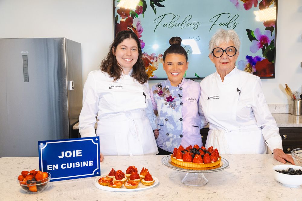 Professional chefs prepare colorful desserts and pastries in a bright commercial kitchen setting.