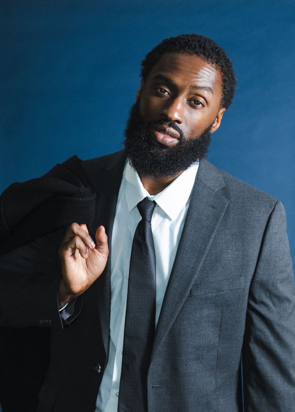 Professional portrait series of a person in a gray suit and tie against a blue background in various poses.