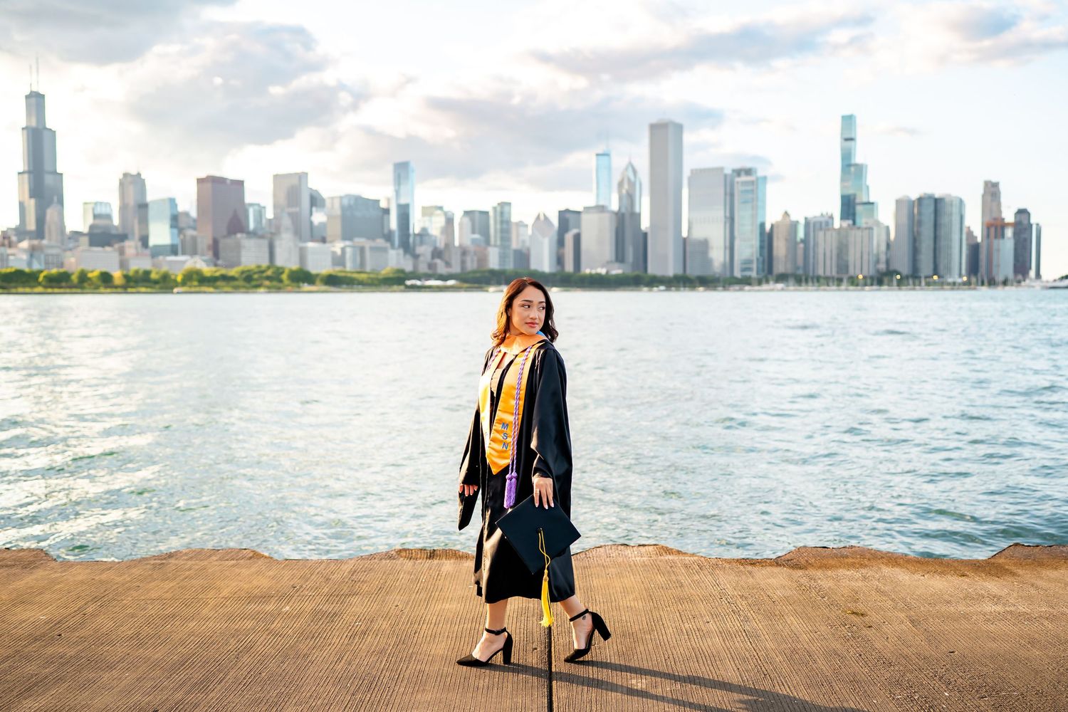 A person stands on a wooden pier overlooking Lake Michigan with Chicago's iconic skyline in the background.