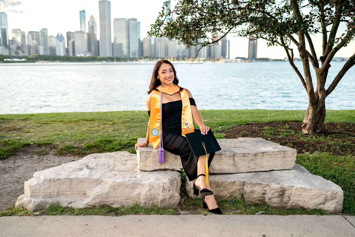 Urban skyline view with figure sitting on large stone by waterfront in Chicago.