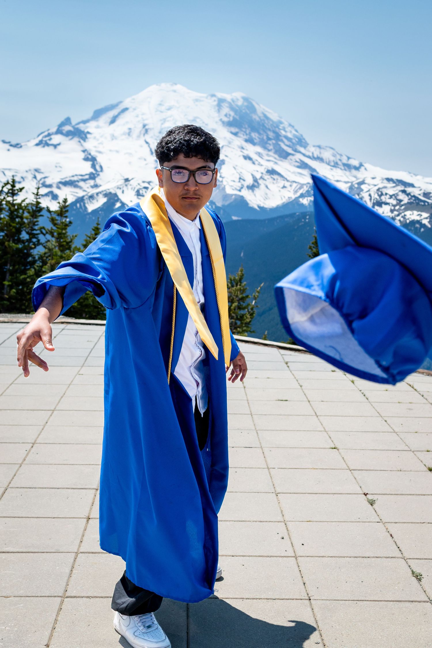 Seattle graduation photographer capturing student celebrating in cap and gown with Mt. Rainier in background