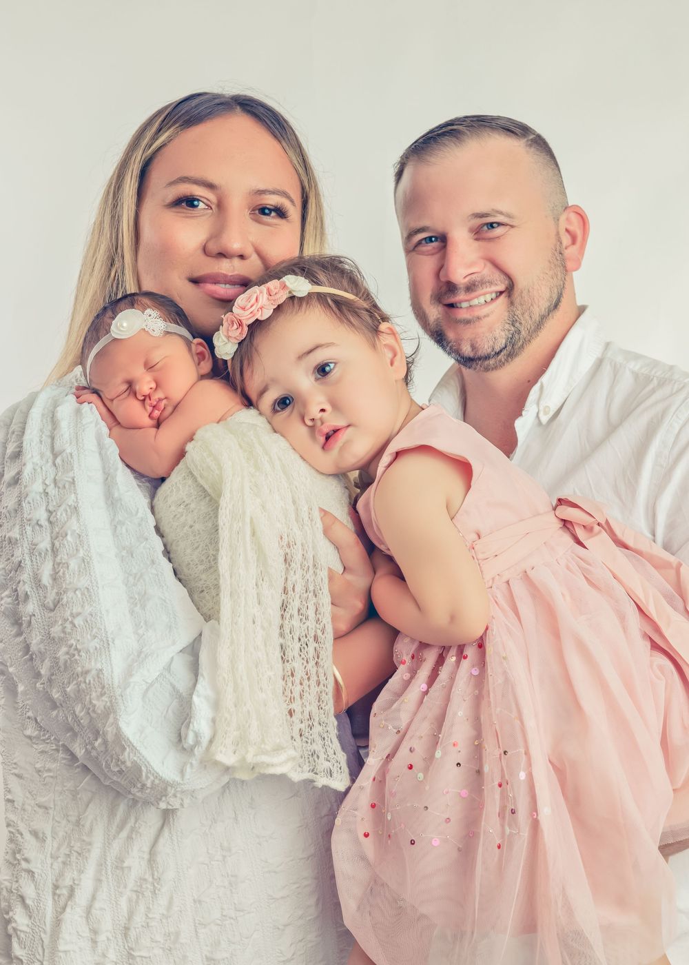 Family portrait session featuring soft white and pink color scheme against light background.