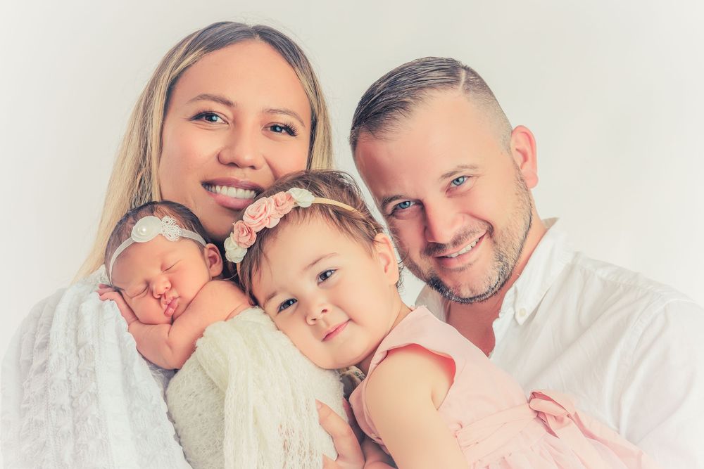 Loving family portrait series in white and pink against neutral backdrop.