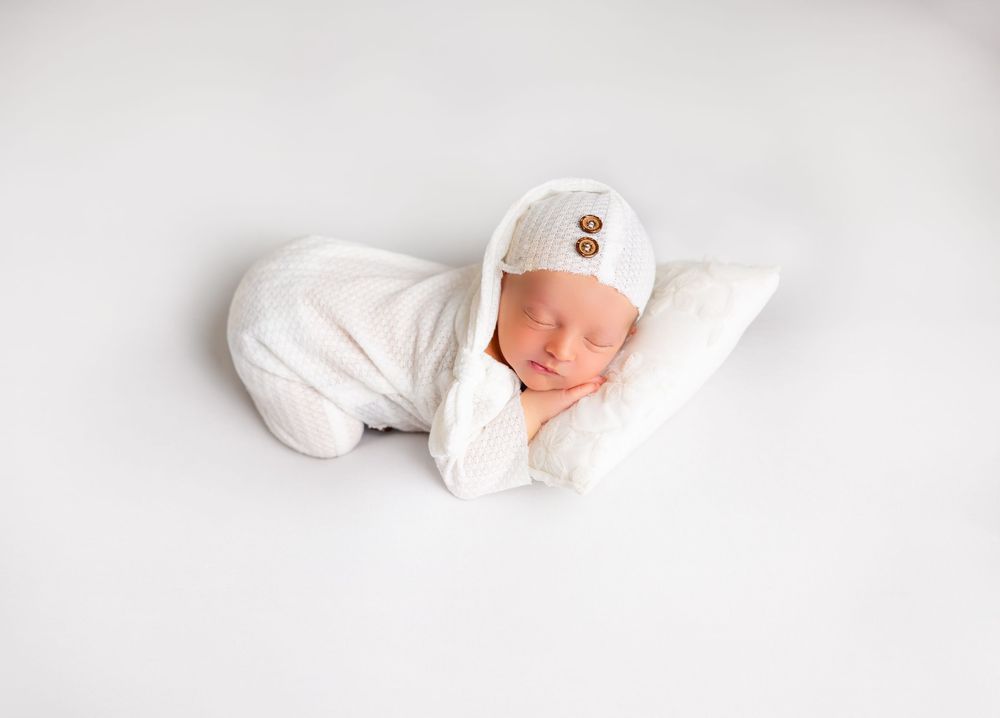 Peaceful baby sleeping on clean white background during minimalist photo shoot.