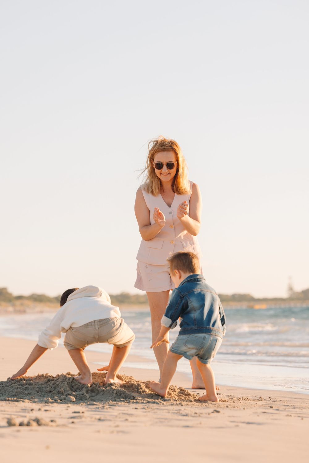 Two people building sandcastles together on a sunny beach.