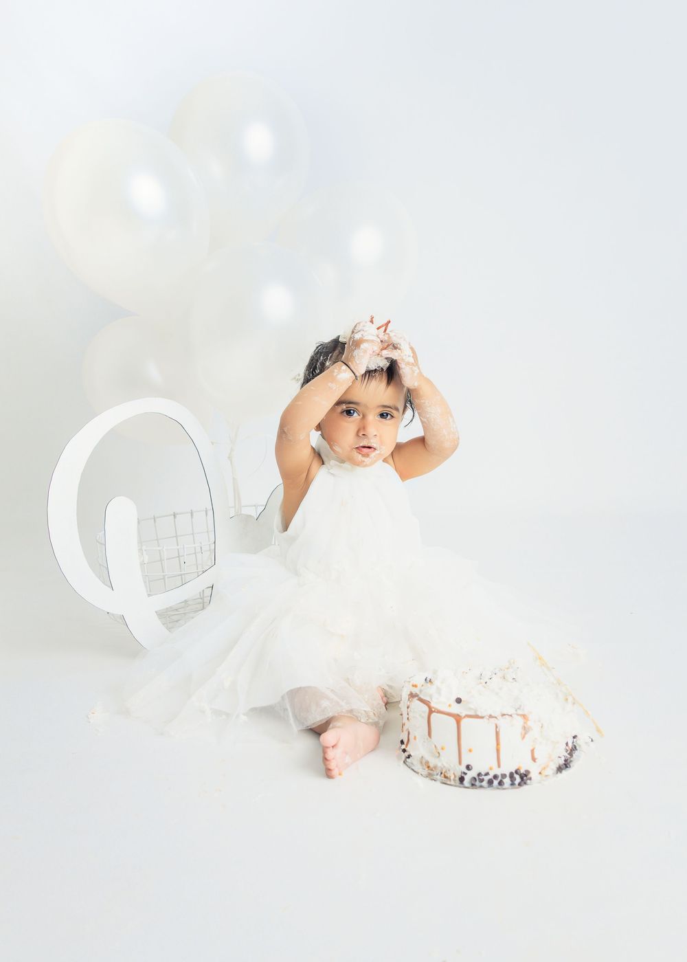 A small child in white clothing and a crown poses in various playful positions against a light background.