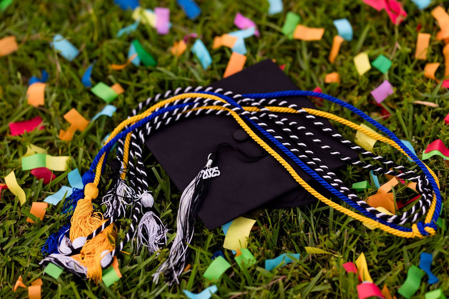 Colorful graduation tassels and cords laying on grass. Photos by Tampa Photographer DigitalMyst Photography