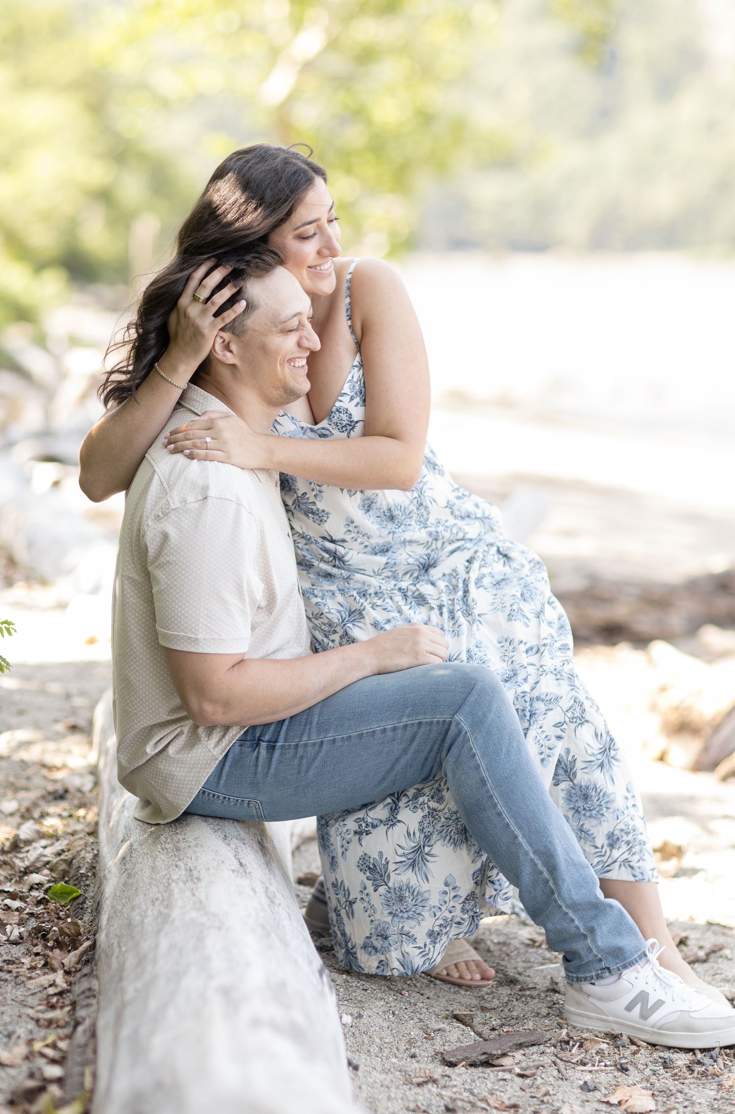 A couple shares an intimate moment outdoors in casual attire against a soft bokeh background.
