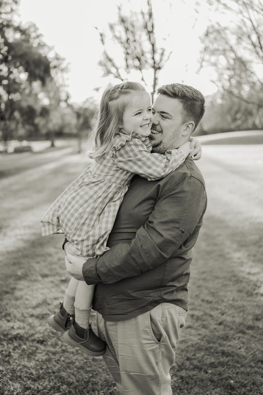 Black and white portrait of a heartwarming embrace between parent and child outdoors.