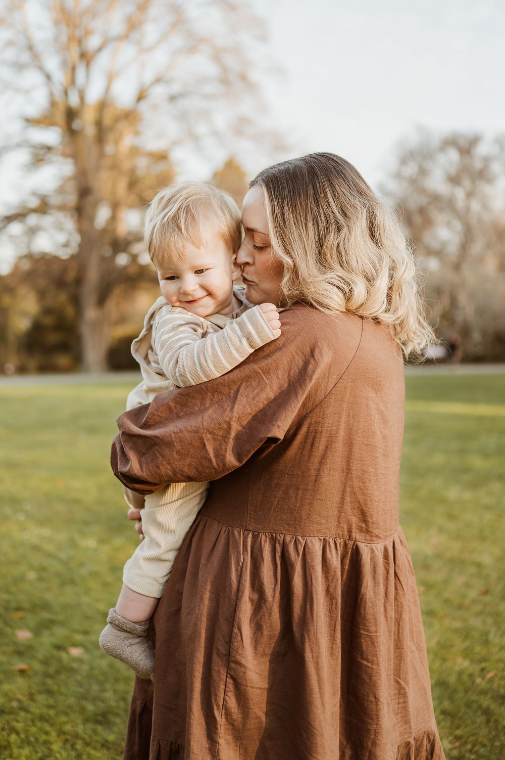 A tender moment between parent and child on a grassy lawn during sunset.