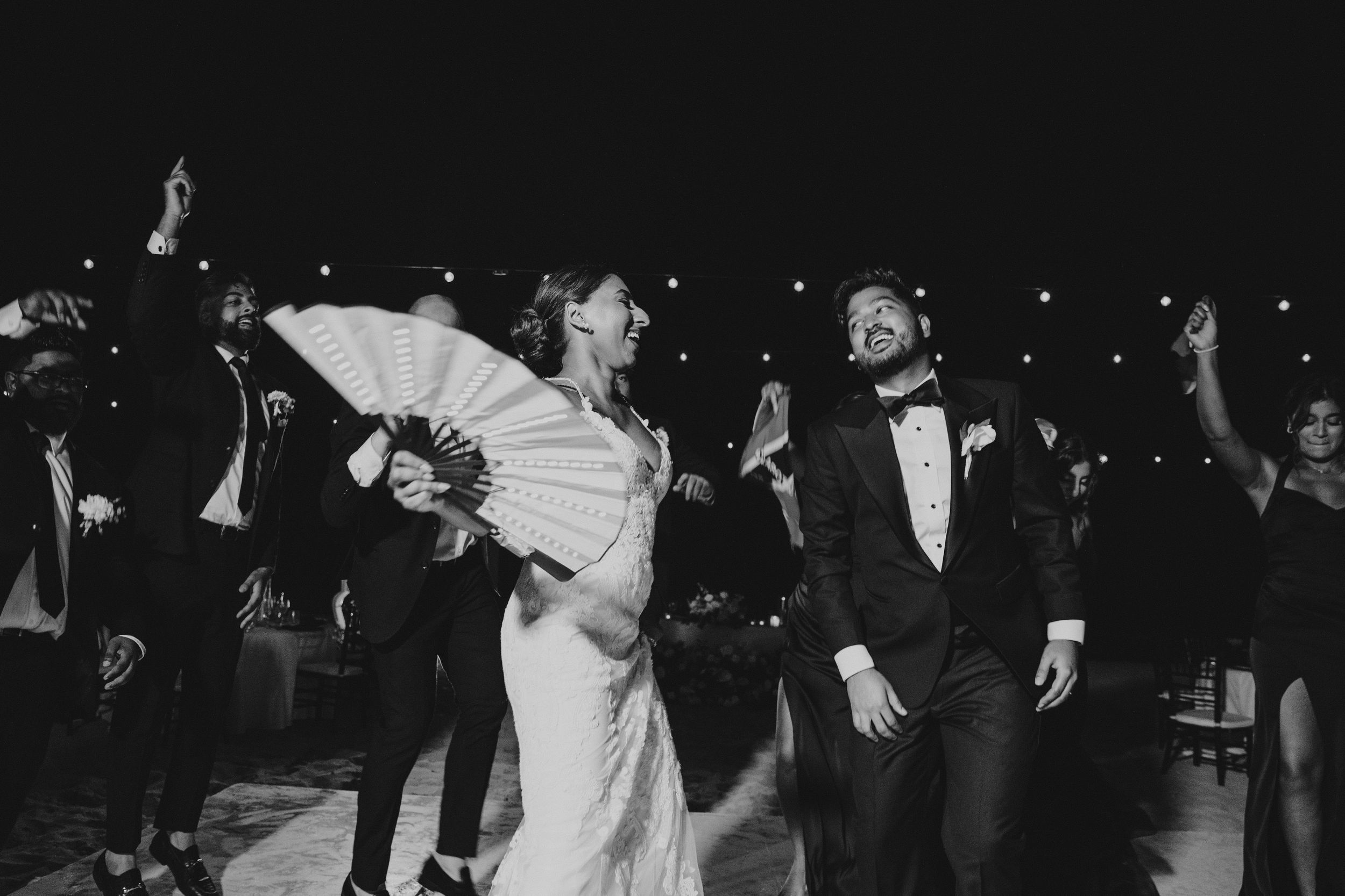 Wedding guests dance and celebrate during a lively nighttime reception.