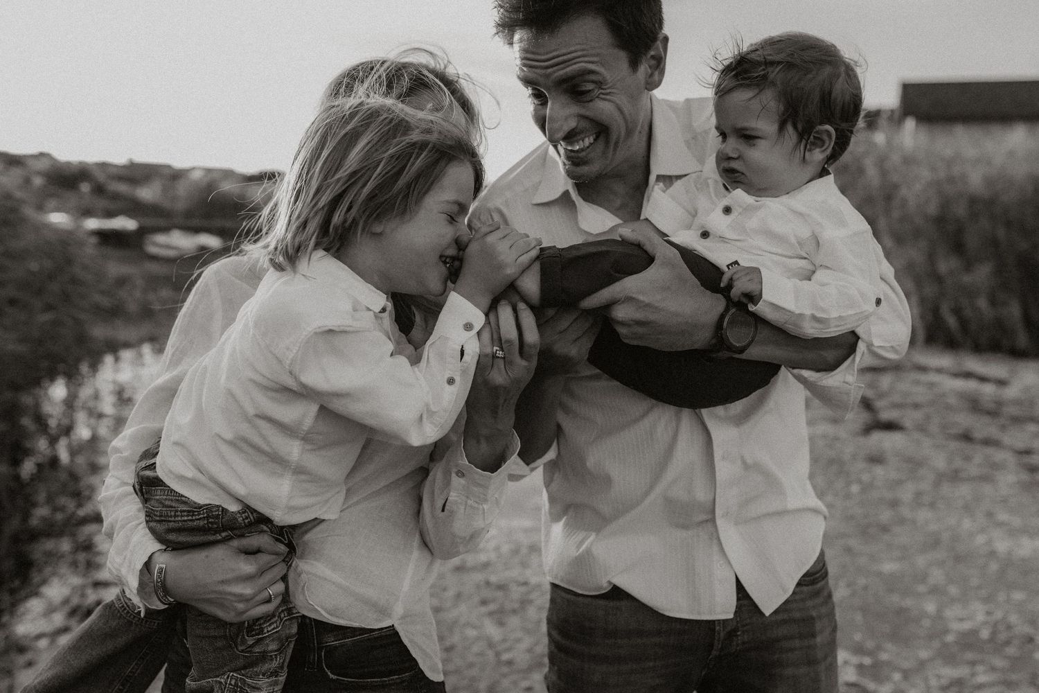Black and white photo collage showing candid family moments outdoors with people laughing and embracing.