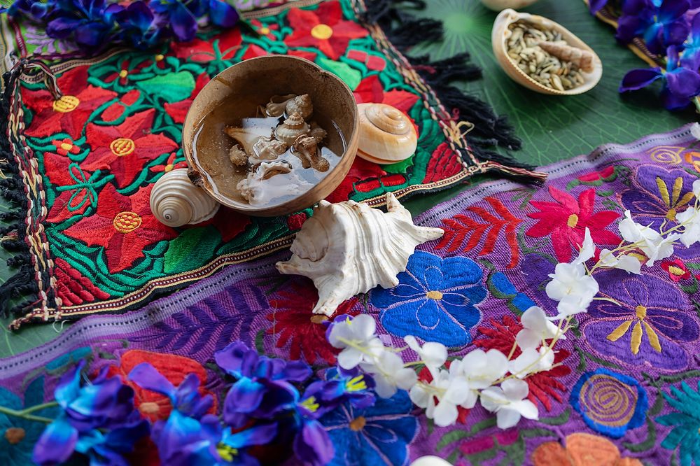 Smudging ritual setup with sage on colorful tribal textile featuring vibrant red and blue floral patterns.