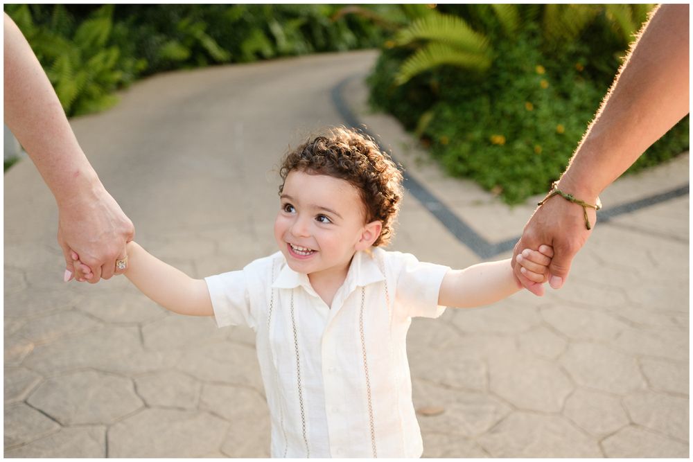 A series of images show small hands holding fingers while walking on stone tile pathway outdoors.