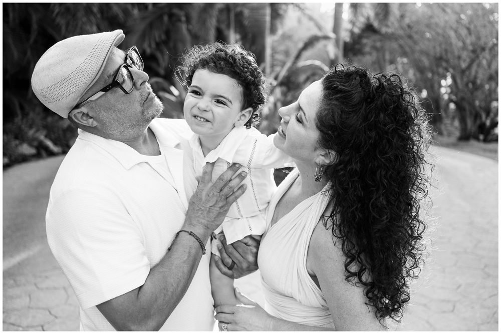 Black and white portrait of a joyful family moment showing three people laughing together outdoors.