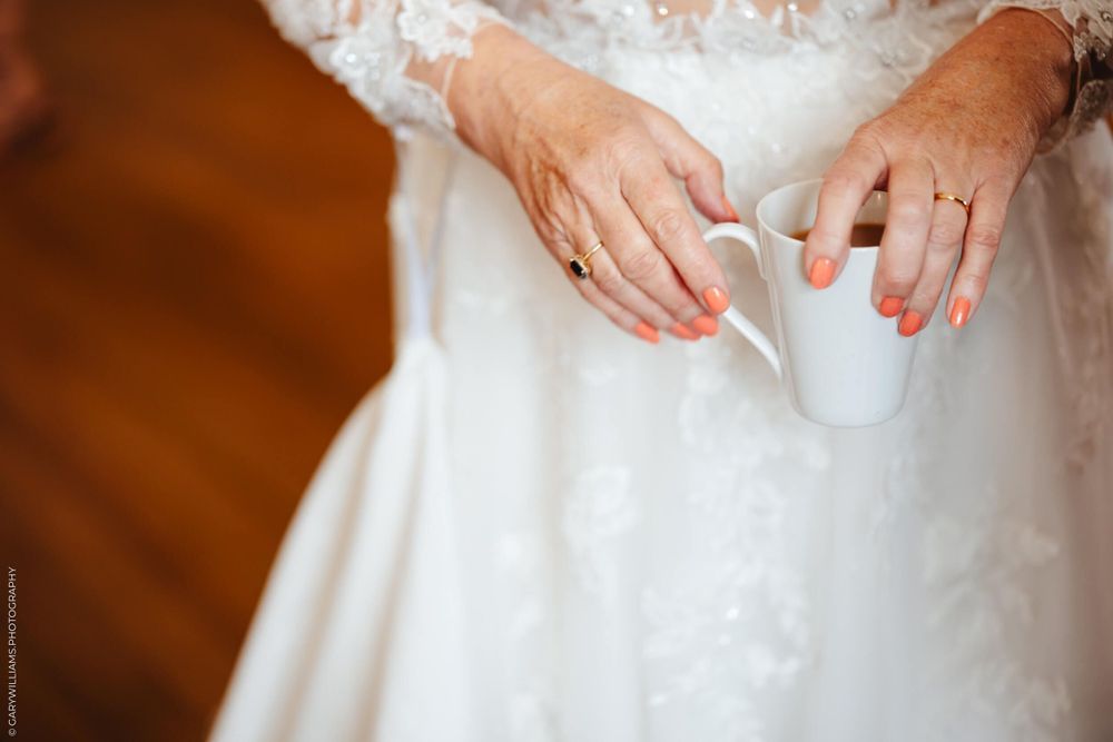 Cropped close-up of ornate beading and lace details on a flowing white wedding dress.