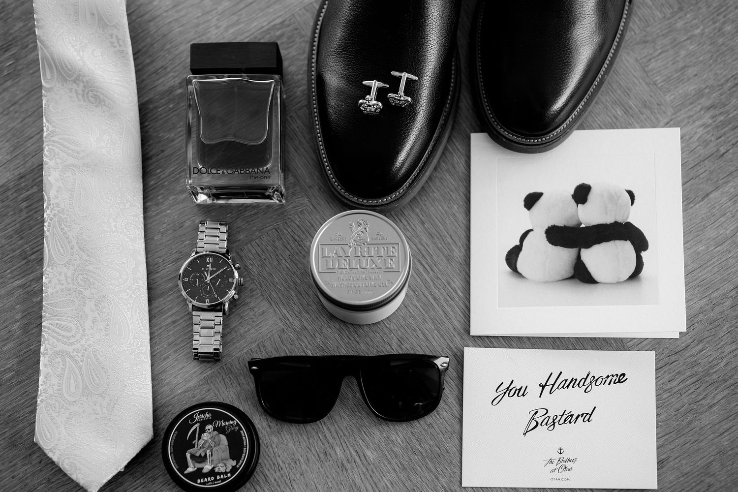 Flatlay photography layout of vintage camera, eyeglasses, tie, and other personal accessories in monochrome style.