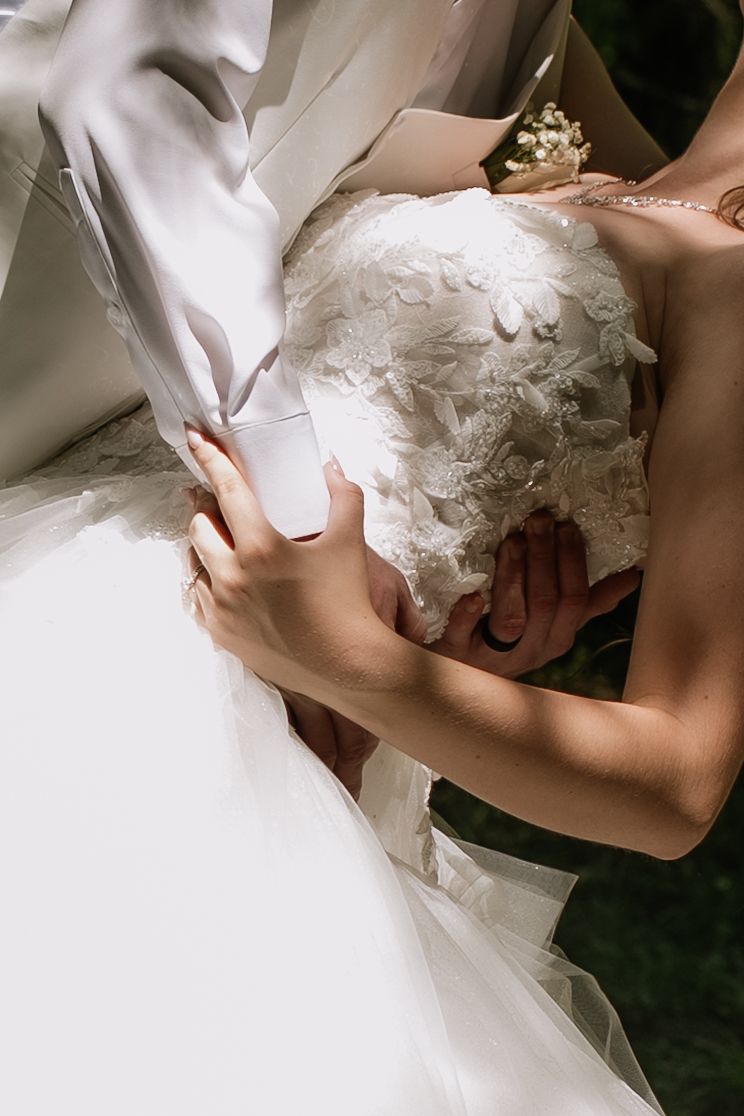 Close-up details of a flowing white wedding dress with delicate lace patterns.
